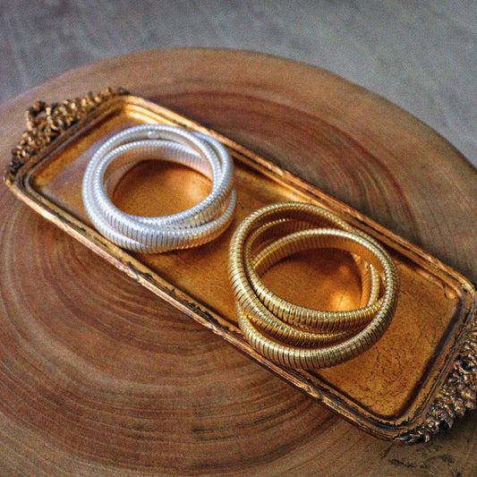 Classic coil bracelet set in gold and silver, flexible stretch design on a decorative tray.