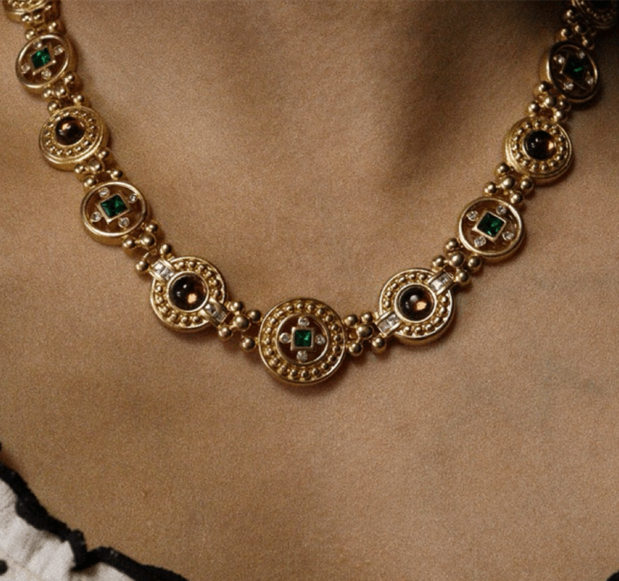 Vintage-inspired gold-plated necklace and bracelet set with gemstone embellishments on display.